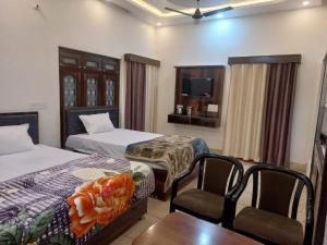AyodhyaKalash Guest House的酒店客房带两张床和一张桌子以及椅子。