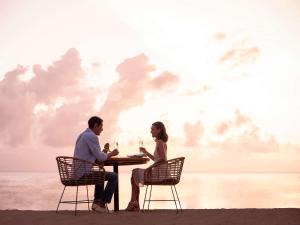 努沙杜瓦巴厘岛努沙杜瓦海滩度假村索菲特酒店的坐在海滩桌子上的男人和女人