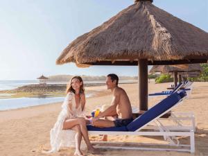 努沙杜瓦巴厘岛努沙杜瓦海滩度假村索菲特酒店的坐在海滩上的男人和女人