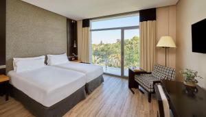 赫雷斯-德拉弗龙特拉NH阿维尼达赫雷斯酒店的酒店客房设有两张床和窗户。