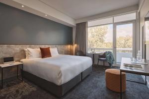 阿德莱德Hotel Alba Adelaide的酒店客房设有一张大床和一张书桌。