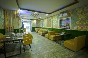 瑞诗凯诗Q Saina S K Regency Rishikesh的用餐室配有桌子和黄色椅子,墙纸
