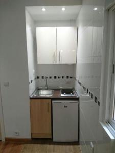 马德里Apartamentos EconoStay Barbieri 1的厨房配有白色橱柜、水槽和窗户。
