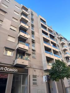 甘迪亚Piso en Gandía的一座高大的公寓楼,前面有一棵树