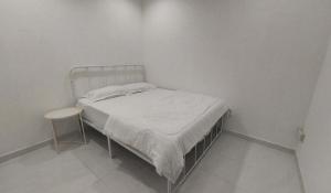 居林D'Sandra Homestay的一间白色的小卧室,配有一张床和一张桌子