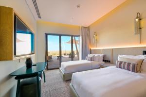 沙迦Al Badayer Retreat by Sharjah Collection的酒店客房设有两张床和一张桌子。