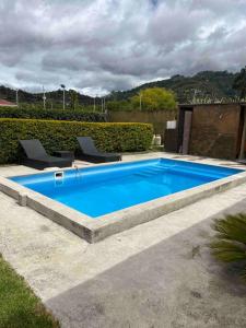 PauteAlegre villa con piscina para uso familiar de 3 dormitorios的一座大型蓝色游泳池旁配有两把椅子