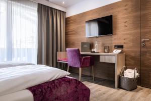 萨尔巴赫索奈格酒店的一间卧室配有一张床、一张书桌和一台电视。