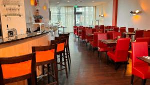博特罗普博特罗普莱茵鲁尔酒店的一间设有红色椅子的餐厅和一间酒吧