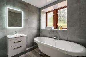 塔滕霍尔Long Ashes - Netherside Barn的浴室配有白色浴缸和水槽