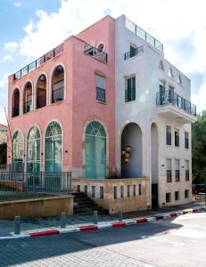 特拉维夫Jaffa Port TLV Hotel Apartments יפו תל אביב的粉红色和白色的建筑,前面设有楼梯