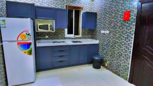 利雅德علم الفريدة للوحدات السكنية المفروشة Alam Faridah Hotel的厨房配有蓝色橱柜和白色冰箱
