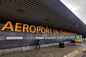 沙勒罗瓦Jumet 242 A Bruxelles-Charleroi-airport的手持标志在建筑物前行走的人