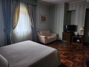 波坦察Dimora della via Appia PRETORIA的一间卧室配有一张床、一把椅子和电视