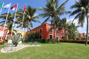 艾库玛尔Bahia Principe Luxury Sian Ka´an - Adults Only - All Inclusive的一座红色的建筑,前面有棕榈树
