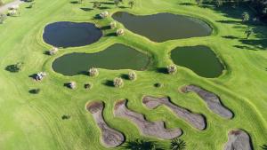 Pico da PedraBatalha Golf Villa的享有高尔夫球场空中景色,设有三个池塘