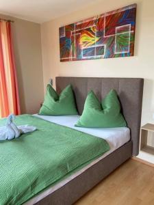 韦因地区拉奇Zweytick Gästezimmer Weingut的一间卧室配有一张带绿色枕头的床和一幅画