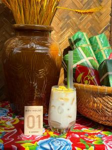 Kon Tum Kơ PangMộc House的蜡烛放在花瓶旁边的桌子上的一个玻璃杯里