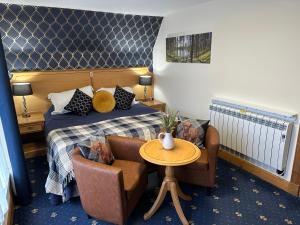 牛顿莫尔The Glen Hotel Newtonmore的酒店客房带一张床、一张桌子和椅子