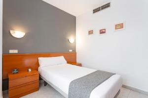托罗Hotel Alda Ciudad de Toro的卧室配有白色的床和木制床头板