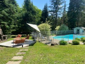 圣阿黛拉Luxury St-Sauveur Chalet with Swim Spa Close to Ski的一个带椅子和遮阳伞的庭院,毗邻一个游泳池