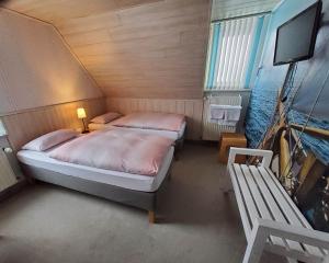 LichtenbergB & B Gästehaus Schmidt的一间卧室配有两张床、一台电视和一张长凳。