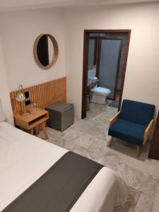 乔卢拉CHOLULA SUITES的一间卧室配有一张床和一张蓝色椅子,还设有一间浴室