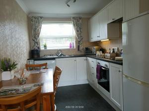 佩文西Cromarty Cottage Eastbourne的厨房配有白色橱柜、桌子和水槽。