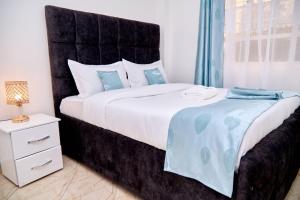 纳纽基Olivet Homes的一间卧室配有一张大床和黑色床头板