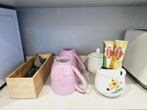 汉密尔顿Hillcrest Home的一个带两个粉红色花瓶和一个木箱的架子
