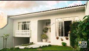 瓜拉普阿瓦HOSTEL INN LAGO的带阳台和植物的白色房屋