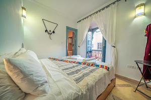 马拉喀什Riad Azawan的一间卧室配有一张带白色床单的床和一扇窗户。