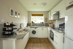 佩文西Harbour cottage sleeps 4 nr Marina Eastbourne的厨房配有白色橱柜、洗衣机和烘干机