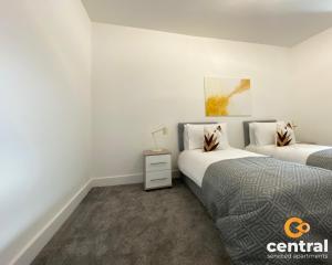 邓迪2 Bedroom Apartment by Central Serviced Apartments - Monthly Bookings Welcome - FREE Street Parking - WiFi - Smart TV - Ground Level - Family Neighbourhood - Sleeps 4 - 1 Double Bed - 2 Single Beds - Heating 24-7 - Trade Stays - Weekly & Monthly Offers的一间卧室设有两张床和床头柜