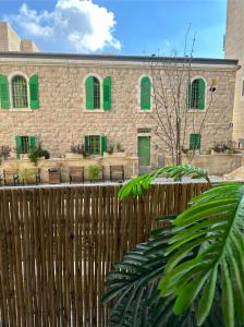 耶路撒冷Jerusalem Center的砖砌建筑,设有绿色窗户和木栅栏