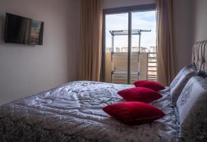 NouaceurLuminous & cosy studio - 5 mins from Mohammed V Airport的一间卧室配有一张带红色枕头的床和一扇窗户