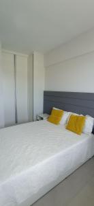 萨尔瓦多Jaguaribe Praia的卧室配有白色床和2个黄色枕头