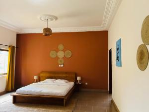 科托努Cocoon Guest House的一间卧室配有橙色墙壁的床