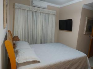 瓜鲁雅Flat Pitangueira com Piscina-Capitânia Varan的一间小卧室,配有一张床和电视