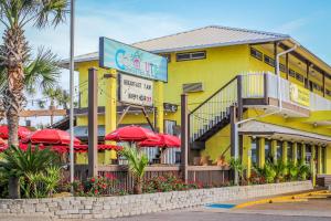 巴拿马城海滩Driftwood Dreams的黄色建筑前的一间餐厅,配有红色遮阳伞