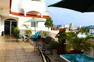 阿卡普尔科D'Cesar Hotel Acapulco的庭院配有桌椅和遮阳伞。
