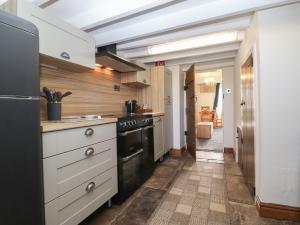 霍伊斯Wether Fell View的厨房配有白色橱柜和黑炉。