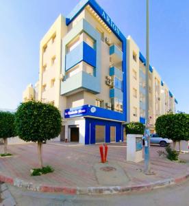 Boumhel El BassatineCoquette Appartement的一座蓝白色的建筑,前面有树木