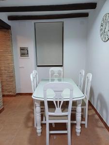 隆达La casita Ronda的一张桌子、白色的椅子和墙上的时钟