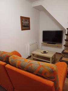 隆达La casita Ronda的客厅配有橙色沙发和平面电视。