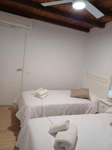 隆达La casita Ronda的白色客房内的两张床和毛巾
