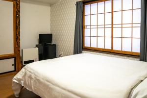 饭山市White Lodge Fukujuso的一间卧室设有一张床和一个窗口