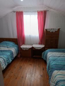 奥索尔诺Cómoda Casa en sector residencial Osorno的一间卧室设有两张床、一个窗户和木地板。