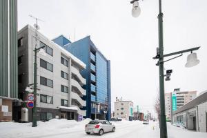 旭川ASTORIA【2min from Asahikawa sta】的一辆汽车驶向城市街道,街道上有许多建筑