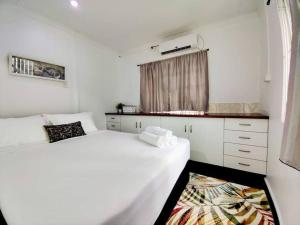 苏瓦Guesthouse in Suva的一间白色卧室,配有两张床和窗户